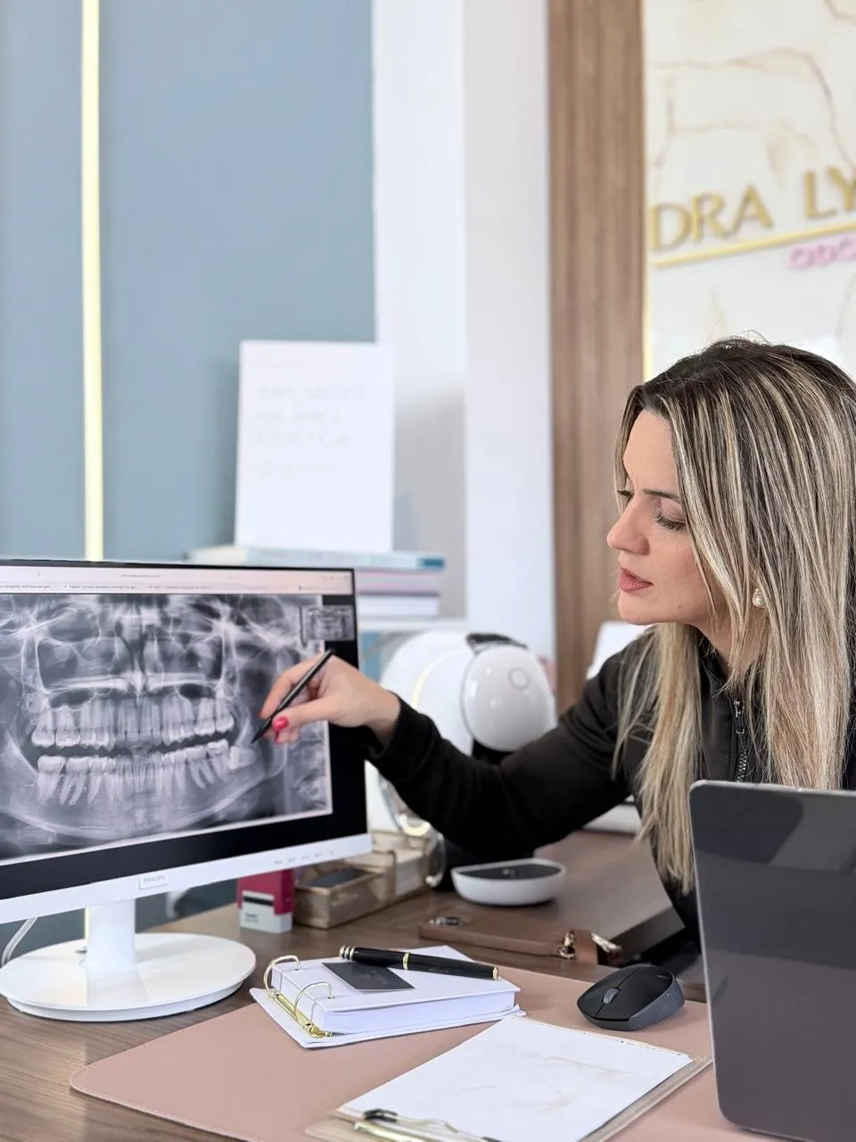 Dra. Lygia Sartorelli analisando uma radiografia panorâmica digital na tela, no consultório